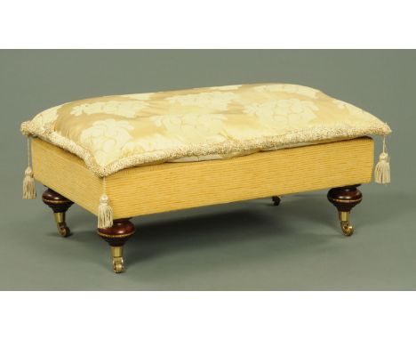 An upholstered stool, originally supplied by Harrods, with loose cushion and raised on four turned legs on brass castors.  Ba