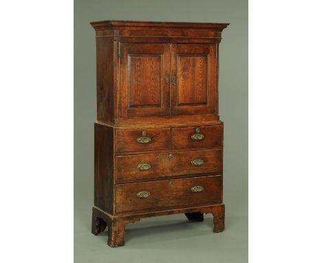 A Georgian oak cupboard, with moulded cornice above a pair of panelled doors, the base fitted with two short and two long dra