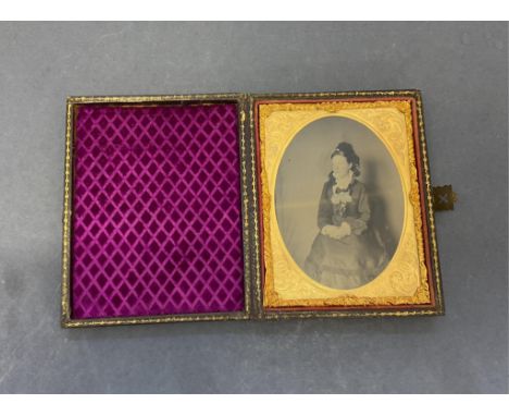 A mid-19th century leather bound cased Daguerreotype portrait of a seated lady, opening to reveal gilt framed photograph, pur
