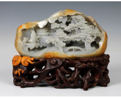 An impressive Chinese jadeite carved boulder, the pale lavender blue and russet boulder carved with an extensive landscape de