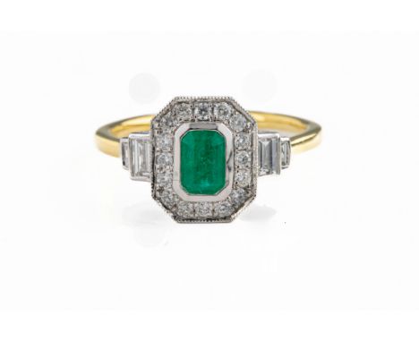 An 18ct white and yellow gold Art Deco style ring, set with a step cut emerald and brilliant and baguette cut diamonds. Emera