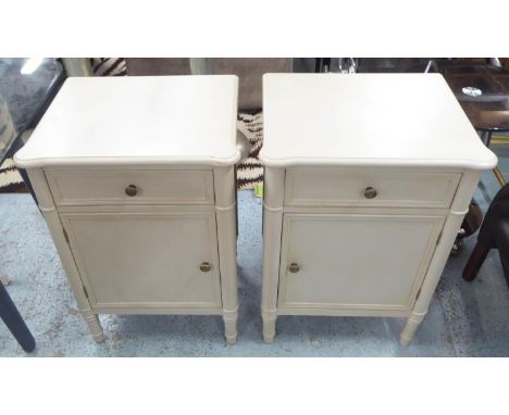 OKA BEDSIDE CABINETS, a pair, 50cm W x 73cm H x 40cm D, in a light grey, each with a short drawer above a panelled door. (2) 