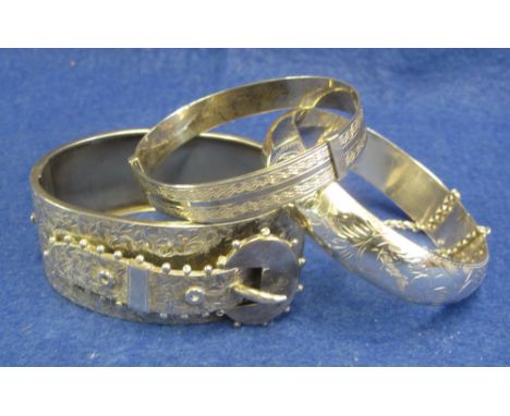 Silver hinged bangle with engraved foliate and applied buckle decoration, together with two other silver bangles. 2ozs approx
