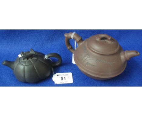 Two Chinese terracotta teapots, the larger decorated with incised characters and foliate designs, the smaller with leaping ca