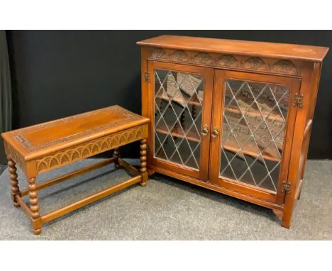 A mid 20th century oak bookcase cabinet, having an oversailing rounded rectangular top above a pair of astral-glazed doors en