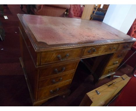 An Edwardian mahogany pedestal desk with leather top and having an arrangement of nine drawers raised on carved bracket feet,