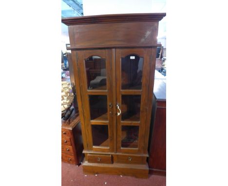A contemporary teak display cabinet with two glazed doors over two drawers, raised on bracket base. H-180cm, W-87cm, D-36cm. 