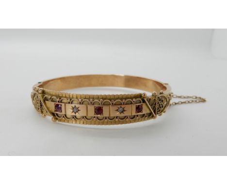 A 9ct gold Etruscan design bangle set with rose cut diamonds and red gems, inner dimensions 5.8cm x 5.3cm, weight 17gms Condi