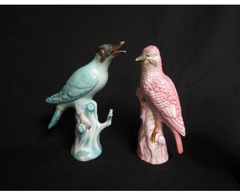 Two 19th Century German porcelain figures of birds, one hand-painted in pink, the other in turquoise, each standing on a tree