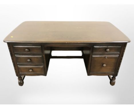 An Ercol stained elm twin pedestal desk, 138 cm x 76 cm x 72 cm 