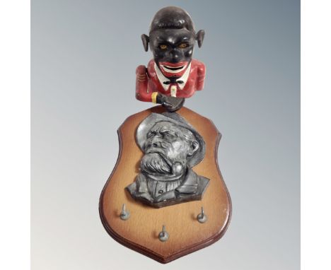 A cast iron novelty money box together with a three hook key rack with embossed plaque depicting a man smoking pipe on shield