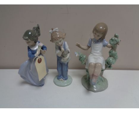 A Lladro figure - Girl seated in tree together with two other Nao figures 