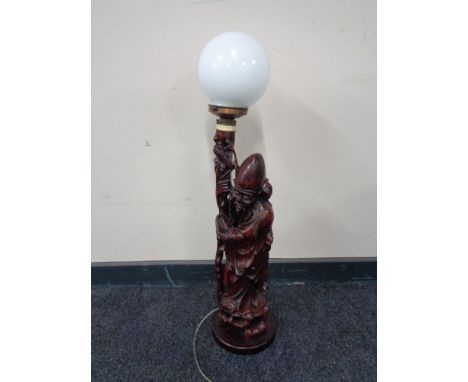 A carved hardwood figural table lamp : Chinese elder, with a circular glass shade 