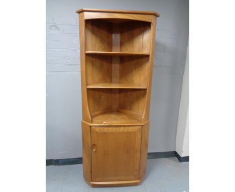 An Ercol elm corner cupboard fitted with shelves above 