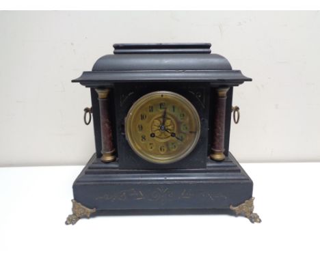 A late nineteenth century French ebonised mantel clock on brass paw feet 