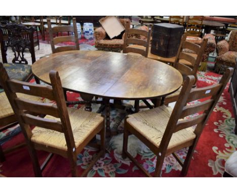 An oak dropleaf dining table, elliptical top with fall leaves, turned supports and stretchers; a set of six similar ladder ba