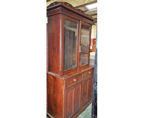 An early 20th century mahogany library bookcase, shaped and pierced cornice above a pair glazed doors, the projecting base wi