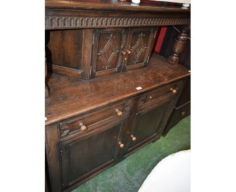 An oak court cupboard, rectangular top above a nulled frieze and a pair of small doors, the base with two short drawers above