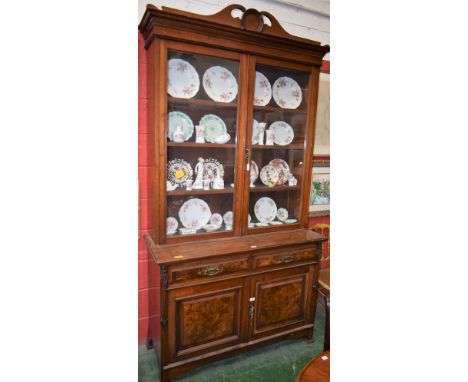 A late Victorian Art Nouveau walnut and mahogany library bookcase, outswept cornice with swan neck pediment centred by a vaca