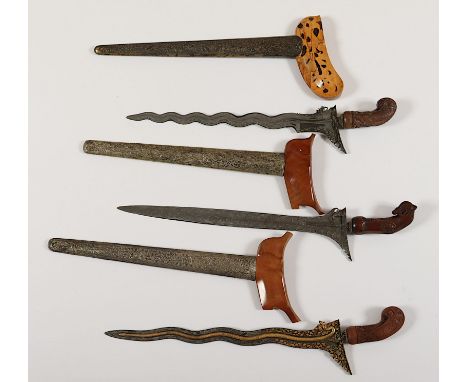 drei Kris, Rasenerzklingen, teilweise beschnitten und vergoldeter Dekor, beschnitzte Holzgriffe, Wrangka und Scheide Holz, Sc