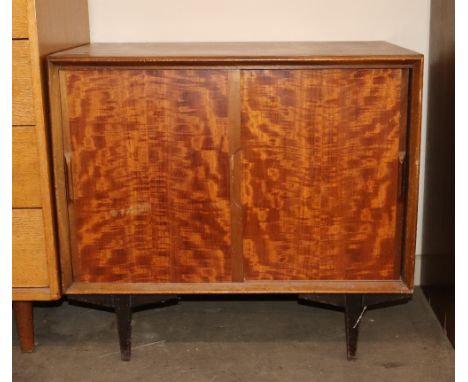 A 1960's / 70's teak low cabinet fitted single shelf enclosed by sliding doors, raised on square tapering supports, 76cm wide