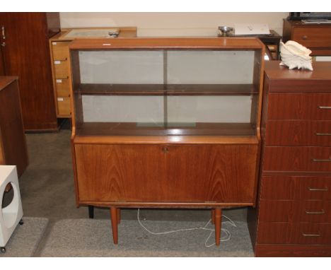 A teak side cabinet, the upper shelf enclosed by a pair of glazed sliding doors with drop flap compartment below, raised on r