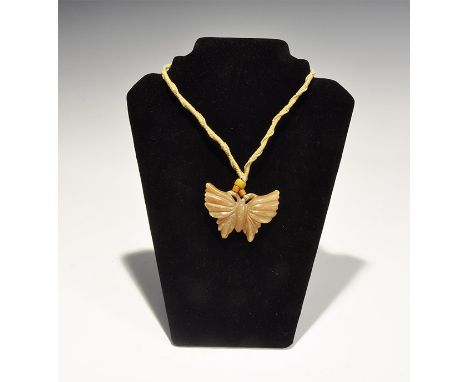 "19th-early 20th century AD. A carved jade butterfly with antennae recurved to form suspension loops; plaited and coiled cord