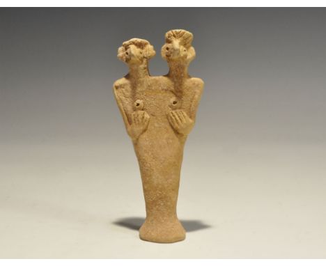 "1180-700 BC. A flat-backed ceramic figurine depicting a female with two heads; the eyes and breasts domed with round recesse