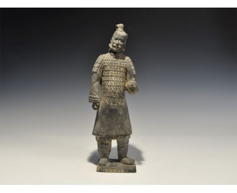 "20th century AD. A greyware ceramic figurine of a warrior in studded coat of plates with baggy trousers and boots; left hand