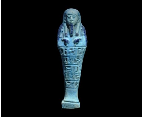 ". An undated archaistic pale blue glazed composition shabti in Late Period, 664-332 BC style, with tripartite wig, agricultu