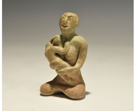 "14th-16th century AD. A green-glazed ceramic figurine of a nude seated female suckling a baby; hollow to the underside. 227 