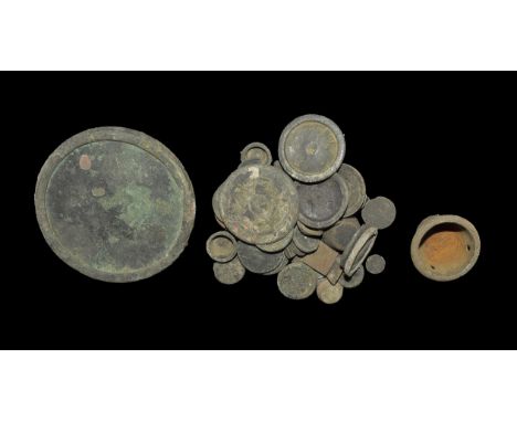 "14th-18th century AD. A mixed group of mainly discoid bronze weights with raised rim, and a bronze vessel with three holes f
