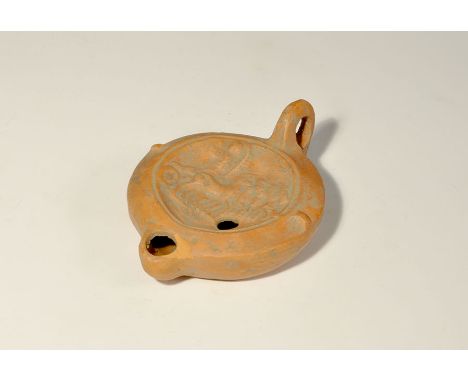 2nd-3rd century AD. A terracotta discoid oil lamp with chamfered shoulder and lateral lugs, pierced lug handle, short nozzle;