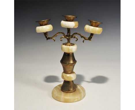 "20th century AD. A candlestick formed as a column of alabaster plaques and conical brass elements, scrolled brass arms with 