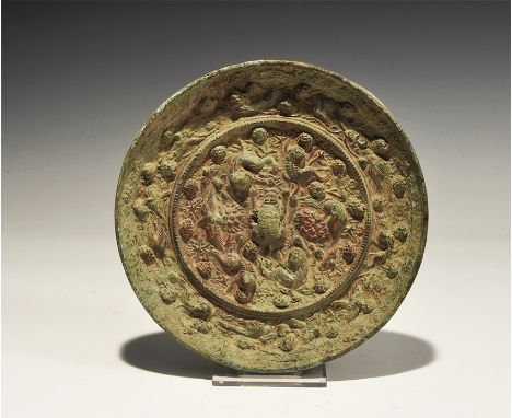 ". An undated archaistic bronze discoid mirror with detailed animal and floral decoration, inner circle with lions and birds 