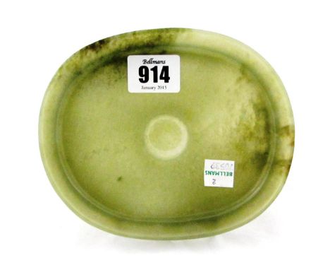 A Chinese celadon jade saucer dish, 17th/18th century, of oval form with everted rim, carved with a circular ring to the cent