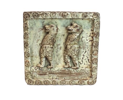 A Burmese glazed pottery square tile, early 19th century, moulded in high relief with two demon-head warriors inside a border