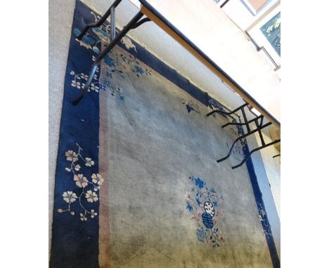 A Chinese carpet, the plain brown field with a central floral motif, sprays to edge and over plain dark indigo border, 300 x 