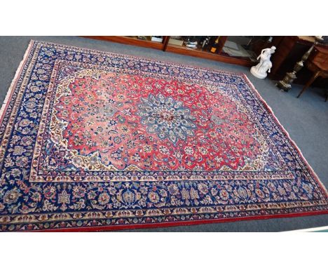 A Kashan carpet, Persian, the madder field with a pale indigo rosette medallion, ivory spandrels, all with floral sprays, an 