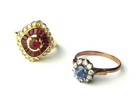 An 18ct gold, ruby and diamond set cluster ring, claw set with the principal circular cut ruby at the centre, within a surrou