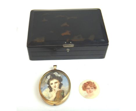 An oval portrait miniature of a lady with brown hair, holding a book, a circular unmounted portrait miniature of a child, wit