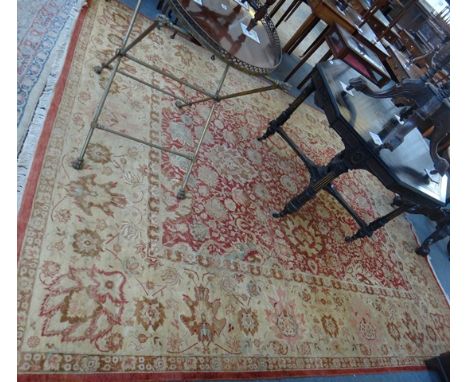 A Pakistan carpet of Persian design, the madder field with an allover palmette and vine design, and a wide beige complementar