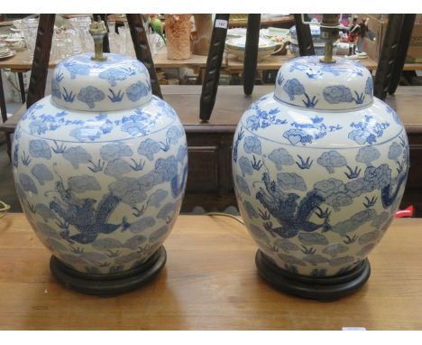 PAIR OF BLUE AND WHITE HANDPAINTED AND GLAZED CERAMIC TABLE LAMPS ON STANDS, DECORATED WITH MYTHICAL DRAGONS 