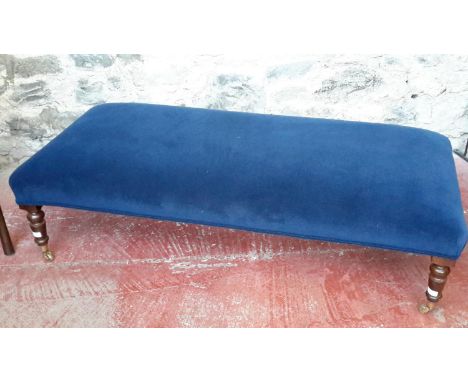 A large blue velvet upholstered pouffe stool on wooden & brass castor feet, 41x148x65cm 