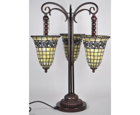 A contemporary Tiffany manner table lamp light. Having a three arm central column with tapering lead glass uplight shades. Bo