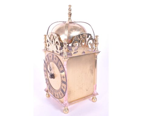 Early 20th century brass lantern clock. Raised on bun feet with Roman numeral chapter ring, dome top with fish figures and fi