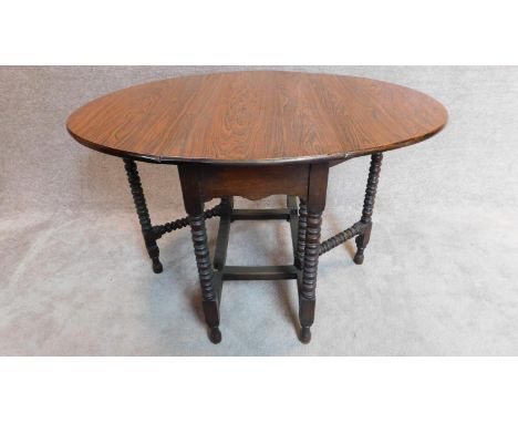 An oak drop flap dining table on bobbin turned supports with a faux rosewood veneered top. H.76 W.120cm 