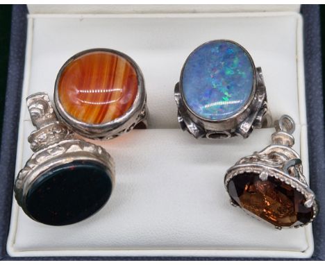 Four items of silver jewellery; Silver and boulder opal ring, Silver and agate stone ring and two silver and stone fob seals.