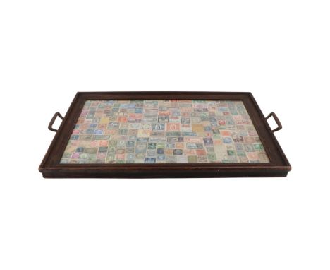 A 1930s philatelic tea tray, being a framed display of 19th Century and later postage stamps under glass within a moulded oak