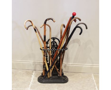A Victorian style cast iron stick stand, the open work upright extending to a rope twist rail enclosing a collection of ten a